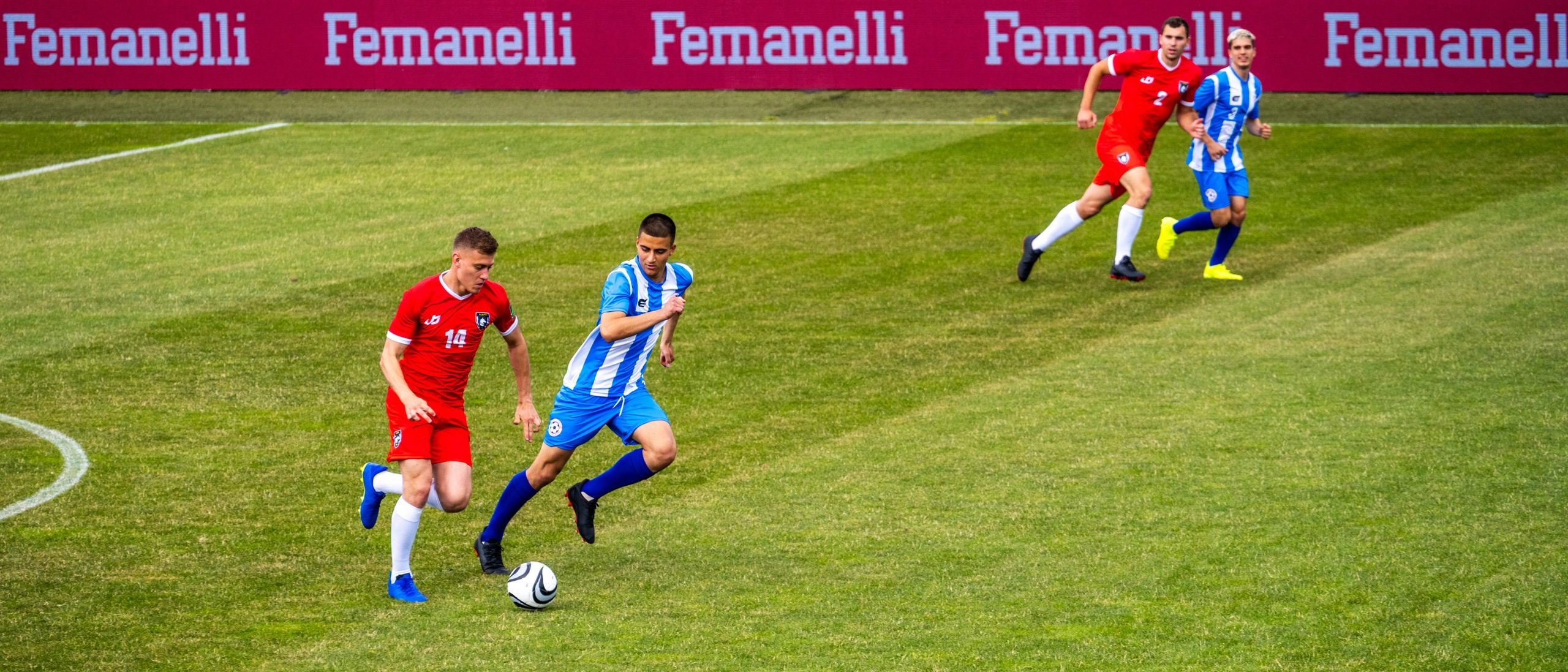 Youth football players running with the ball on a grass pitch