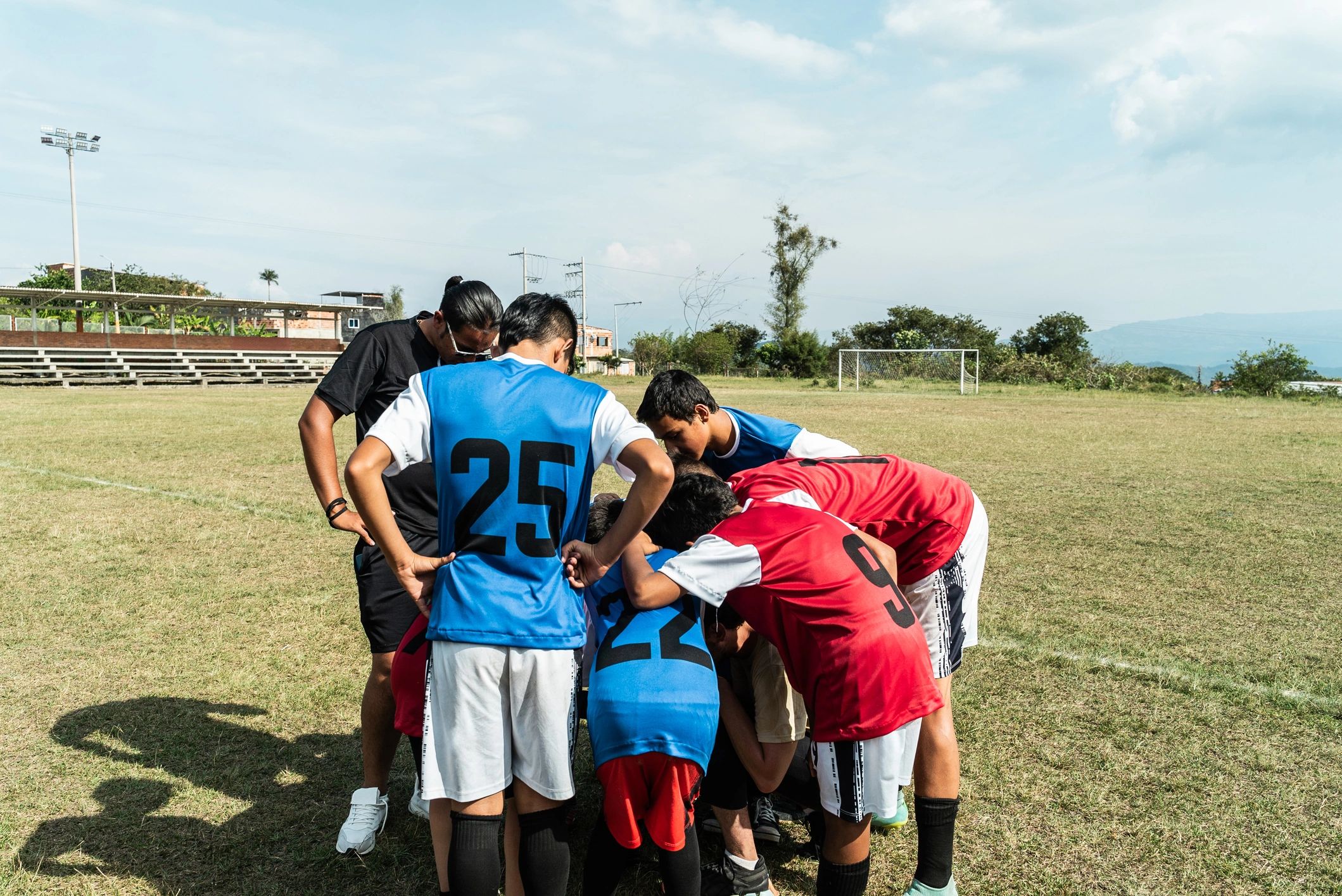 Coach and youth players talking together on a football field