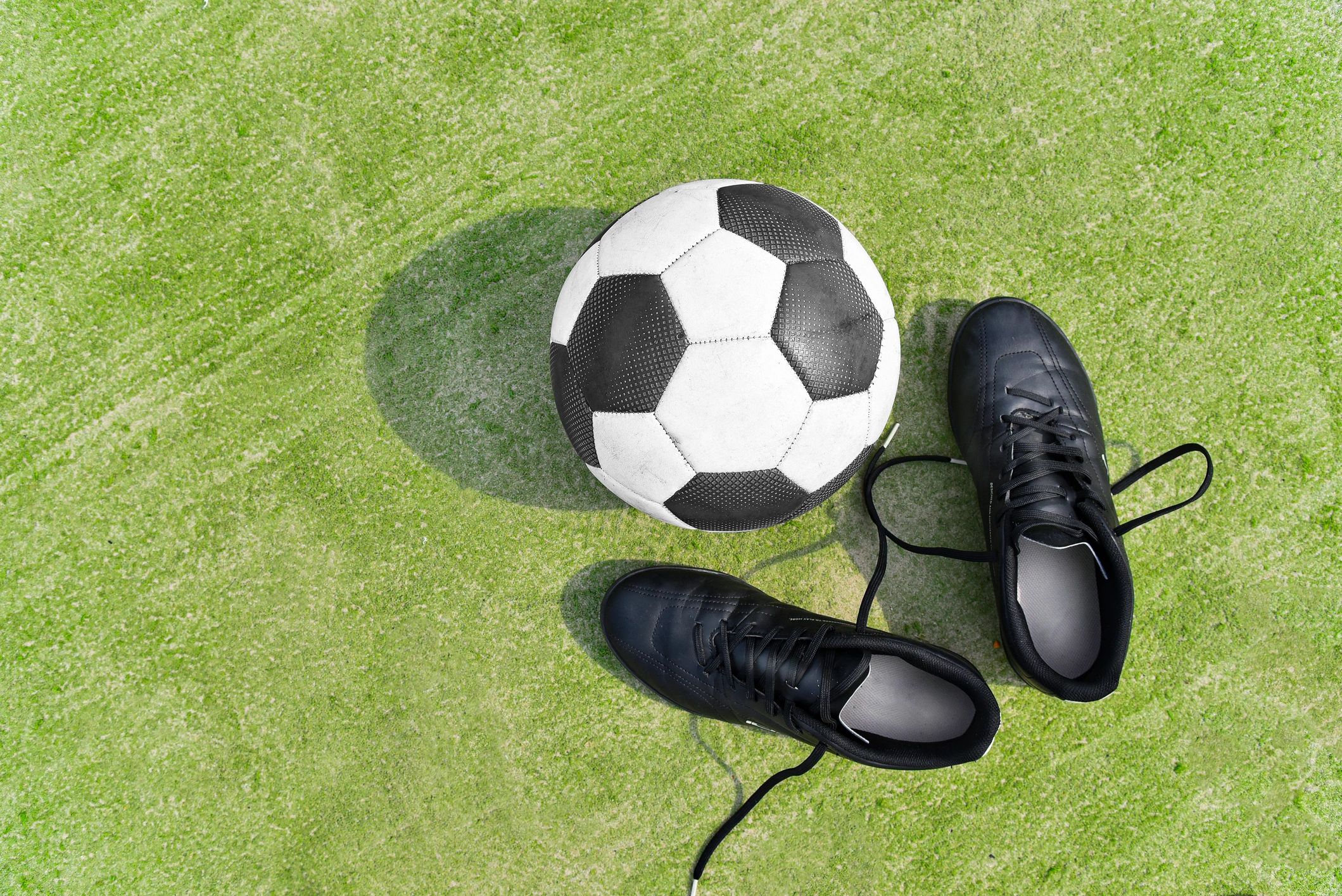 Football boots and ball on a pitch