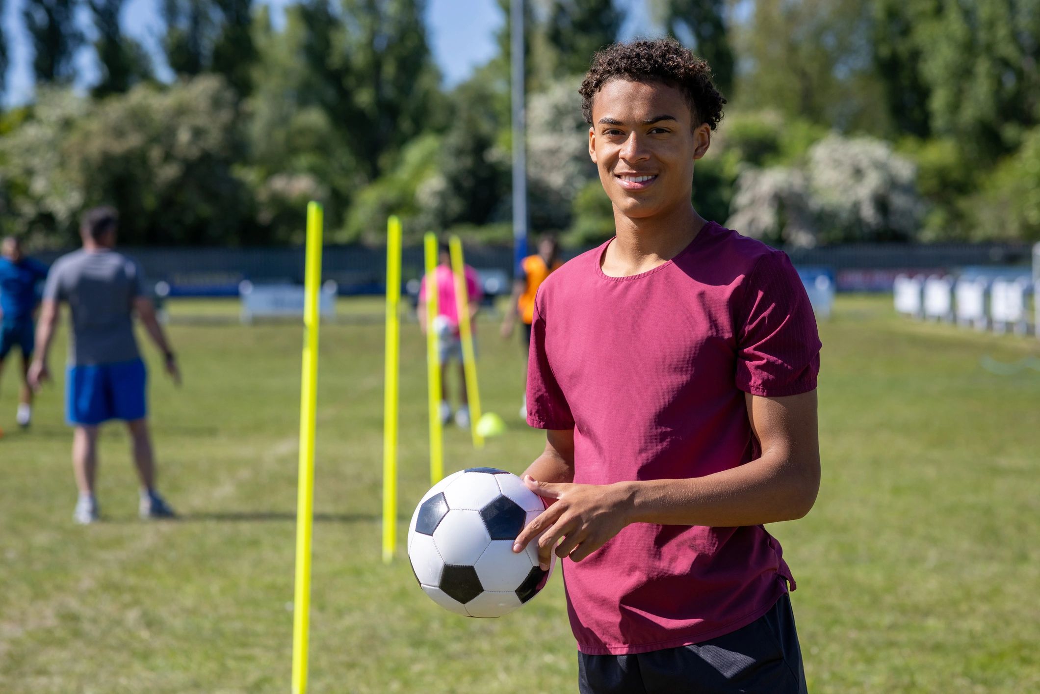 Young football player holding a ball on the pitch